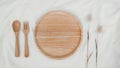 Plate wooden, spoon wooden and fork wooden with Rabbit tail dry flower on white cloth. Mock-up of kitchenware. Top view of Table Royalty Free Stock Photo