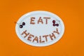Plate with words Eat Healthy made of cherry kernels on orange ba Royalty Free Stock Photo