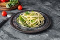 Plate with zucchini spaghetti on grey table