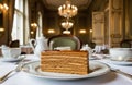Plated caramel-layer Dobos cake on table inside elegant vintage-style salon, surrounded by warm light and classical decor details Royalty Free Stock Photo