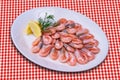 Plateful of cooked shrimps with lemon slice on checked tablecloth Royalty Free Stock Photo