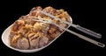 Plateful of Fresh Spit Roasted Pork Meat Slices with Serving Knife and Fork on Oval Porcelain Tray Isolated on Black Background Royalty Free Stock Photo