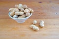 Plateful of Organic shelled peanuts and Spilled shelled peanuts on Wooden Background