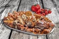 Plateful of Spit Roasted Pork Meat Slices With Bunch of Tomato On Old Wooden Background