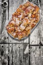 Plateful of Spit Roasted Pork Meat Slices Set on Old Weathered Cracked Wooden Garden Table