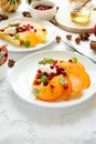 Plates of Belgian waffles with persimmon, pomegranate seeds and sour cream Royalty Free Stock Photo