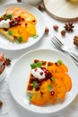 Plates of Belgian waffles with persimmon, pomegranate seeds and sour cream Royalty Free Stock Photo