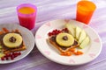 Plates with creative sweet toasts for child and cups of juice on wooden table