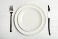 Plates, fork and knife on wooden table, top view Royalty Free Stock Photo