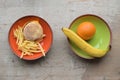 Plates with fruit and burger on the table. Harmful and healthy food to choose