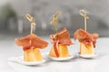 Plates with skewers made of melon bits with cured ham on a table