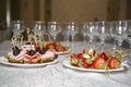 Plates with snacks on skewers and empty glasses on a table covered with a white tablecloth