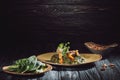 plates with spinach leaves and panikesh near bowl with cashew nuts on wooden