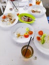 On the white table, there are plates, glasses, dirty spoons used to eat, there are also leftover food.