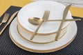 Plates and utensils, Plate, Bowl and golden cutlery on dining table, side view. Modern craft ceramic tableware, cutlery on the Royalty Free Stock Photo