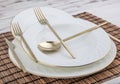 Plates and utensils, Plate, Bowl and golden cutlery on wicker american serving on dining table, side view. Modern craft ceramic Royalty Free Stock Photo