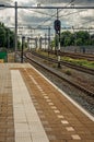 Platform, railroad rails and signaling at train station under blue cloudy sky at Weesp. Royalty Free Stock Photo