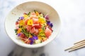 plating colorful poke bowl with raw fish cubes