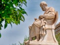 Plato the ancient Greek philosopher white marble statue and orange tree foliage on sky background.