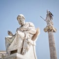 Plato, the philosopher and Athena, goddess of knowledge and wisdom, white marble statues under clear blue sky.