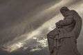 Plato's marble statue, the ancient Greek philosopher in deep thoughts, under an impressive cloudy sky with sun patches.