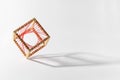 Platonic solid wooden cube with red thread on edge over white background