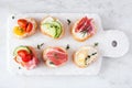 Platter of cream cheese crostini appetizers with an assortment of toppings over a white marble background