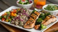 A platter of grilled salmon steamed broccoli and wild rice paired with a refreshing side salad and fruit infused water