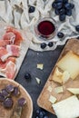 Platter with hard cheeses omemade dried meat, ham jamon serrano or prosciutto crudo, glass of red wine with grapes Royalty Free Stock Photo