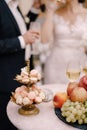Platter of macaroon cakes stands next to a bowl of fruit on the background of the newlyweds Royalty Free Stock Photo
