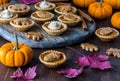 A platter of pumpkin pie tarts surrounded by pumpkins and fall leaves