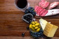 Platter with sliced Italian hard cheese pecorino toscano, homemade dried meat salami, glass of red wine, grape, olives on wooden b