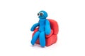 Play dough man sitting on red sofa on white background Royalty Free Stock Photo