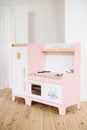 Play furniture for children. Sweet little pink kitchen with fridge, stove, oven and sink in light room