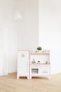 Play furniture for children. Wooden pink and white kitchen with fridge, stove, oven and sink in big light room