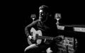 Play the guitar. Beard hipster man sitting in a pub. Guitars and strings. Bearded man playing guitar, holding an Royalty Free Stock Photo