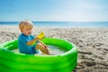 Play in inflatable pool at the beach holding plastic toy ship Royalty Free Stock Photo