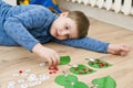 Boy lying on the floor and playing homemade counting game ` ladybird on the leaf `.