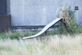 Play park derelict abandoned slide in overgrown grass at playground