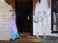 Ladies cloths shop front with painted figures of women on wall.