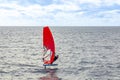 The windsurfer on the board under sail moves at a speed along the surface of the sea, against the background of waves and