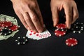 The player bets on a winning combination royal flush in poker game on a black table with chips and money in a club Royalty Free Stock Photo