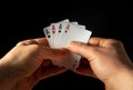 The player hands hold playing cards with a winning combination of four of a kind or quads. Success at poker