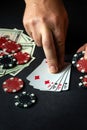 Player points with his finger at a winning four of a kind or quads combination in poker game on a black table with chips and money Royalty Free Stock Photo