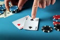 The player points with his finger at a winning one pair combination in poker game on a blue table with chips and money in club Royalty Free Stock Photo