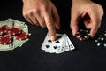 The player points with his finger at a winning straight flush combination in poker game on a black table with chips and money in Royalty Free Stock Photo