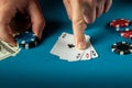 The player points with his finger at a winning three kind or set combination in poker game on a blue table with chips and money in Royalty Free Stock Photo