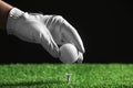 Player putting golf ball on tee against black , closeup Royalty Free Stock Photo