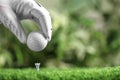 Player putting golf ball on tee against blurred background, closeup Royalty Free Stock Photo