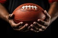 Player's Grasp on the Pigskin: Close-up photo capturing the firm grip of an American football player on the iconic